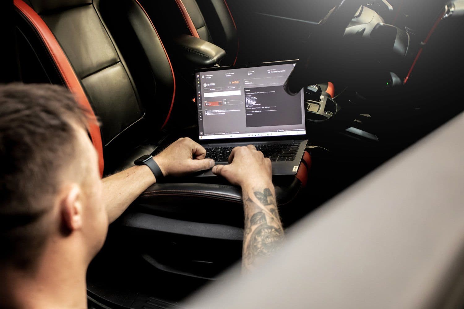 Technician reading live data on a laptop from the driver's seat