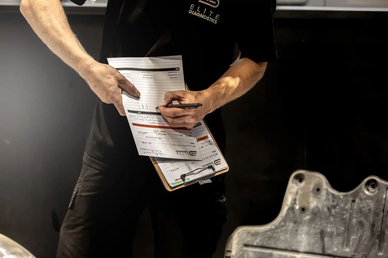 Technician signing off the job sheet on a clipboard